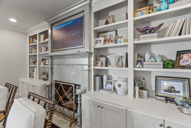 interior space featuring recessed lighting, built in shelves, a high end fireplace, and crown molding