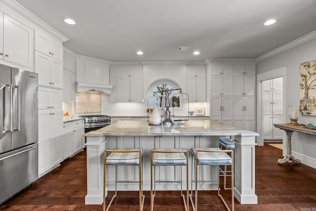 kitchen featuring dark wood finished floors, premium appliances, white cabinets, and light stone countertops