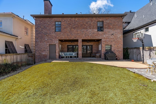 rear view of property featuring a patio, fence, brick siding, and a lawn