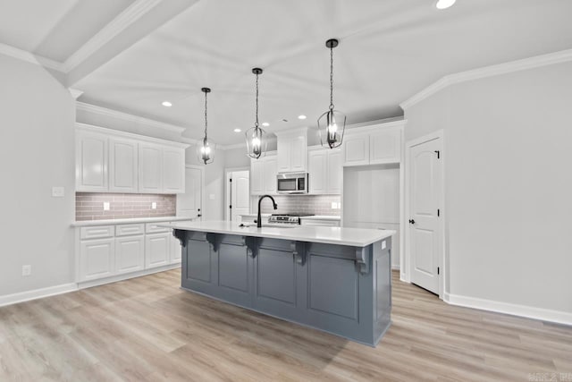 kitchen featuring stainless steel microwave, white cabinets, light countertops, and light wood-type flooring