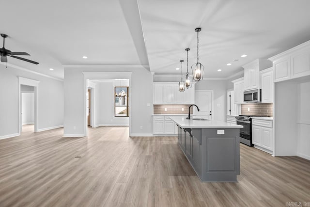 kitchen featuring a sink, open floor plan, white cabinetry, and stainless steel appliances