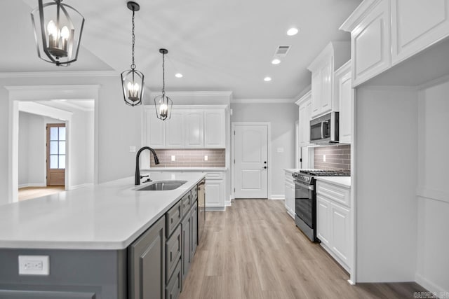 kitchen with a sink, gray cabinetry, light countertops, white cabinets, and stainless steel appliances