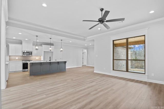 kitchen with white cabinetry, backsplash, open floor plan, and appliances with stainless steel finishes