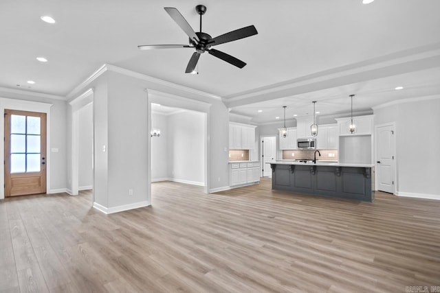 unfurnished living room with crown molding, baseboards, light wood-type flooring, and a sink