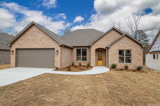 view of front of house with an attached garage, a shingled roof, concrete driveway, a front lawn, and brick siding