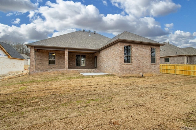 back of property featuring a patio area, brick siding, a yard, and fence