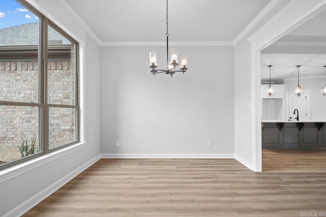 unfurnished dining area with a notable chandelier, crown molding, light wood-type flooring, and baseboards