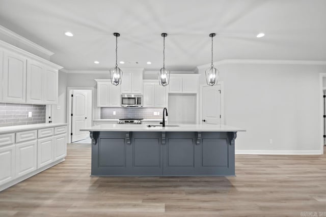 kitchen with a sink, stainless steel appliances, white cabinets, light wood-style floors, and crown molding