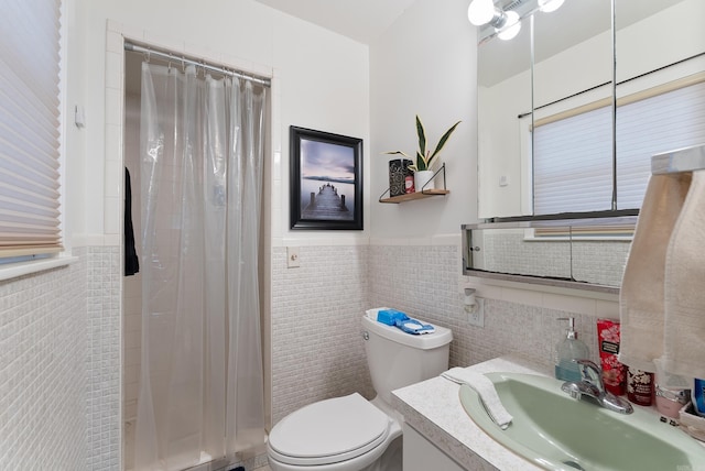 full bath featuring vanity, a shower with curtain, a wainscoted wall, tile walls, and toilet