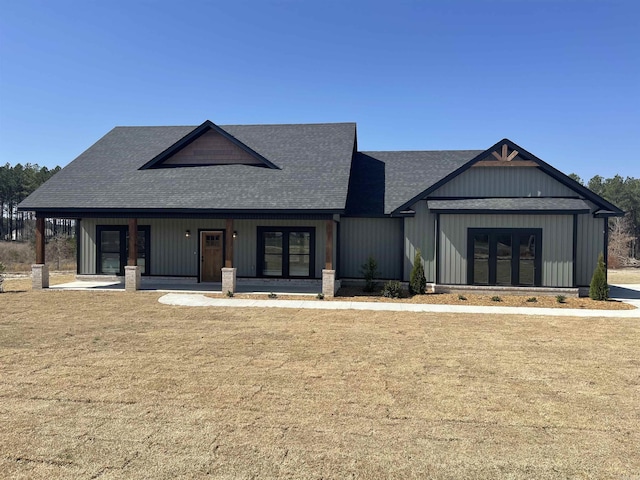 modern farmhouse featuring a front lawn, a porch, and roof with shingles