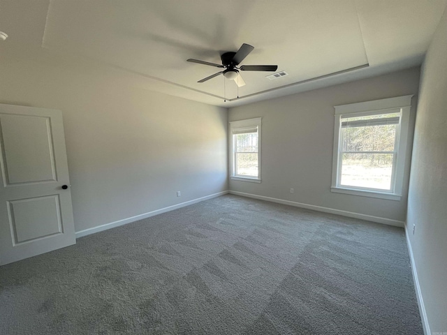 carpeted spare room with visible vents, ceiling fan, and baseboards