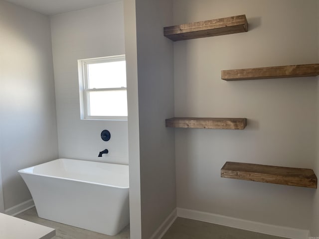 bathroom with a soaking tub and baseboards