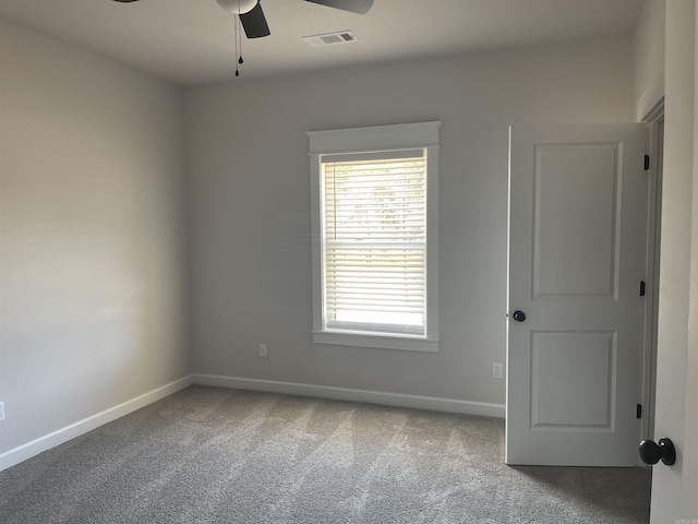 carpeted spare room featuring visible vents, baseboards, and a ceiling fan