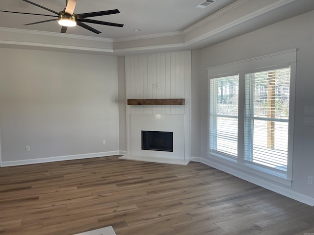 unfurnished living room with a fireplace, wood finished floors, baseboards, and ornamental molding