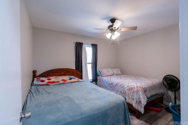 bedroom featuring baseboards, wood finished floors, and a ceiling fan