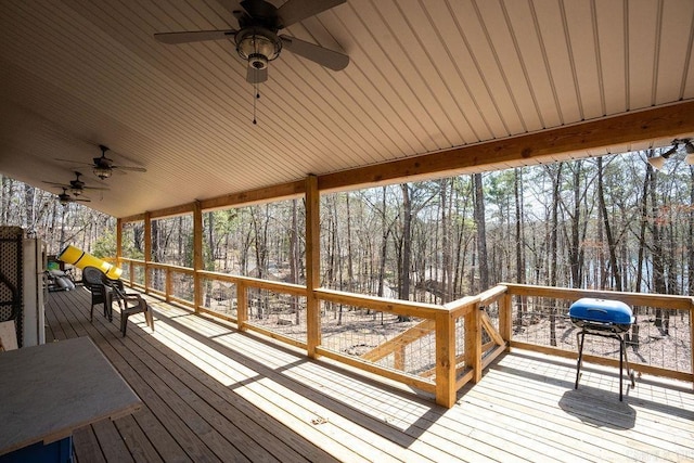 wooden terrace featuring a view of trees and ceiling fan