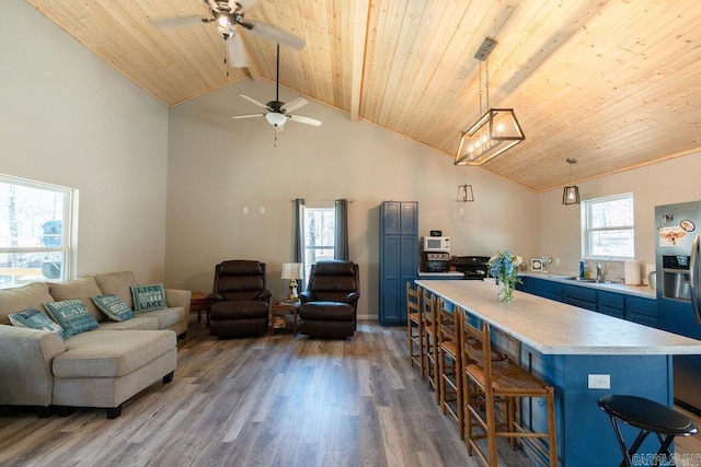 kitchen featuring a kitchen bar, blue cabinets, stainless steel fridge with ice dispenser, and open floor plan