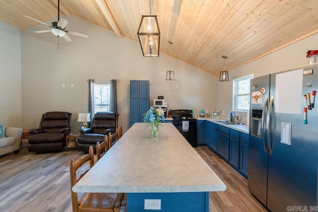 kitchen with blue cabinets, stainless steel refrigerator with ice dispenser, a sink, black range with electric cooktop, and light countertops