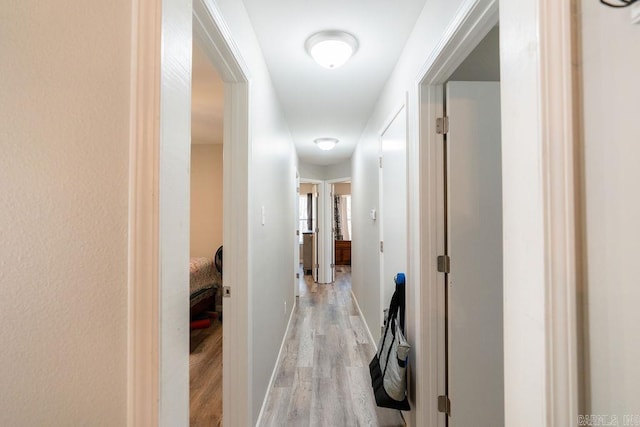 corridor with light wood finished floors and baseboards