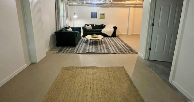 living area with baseboards and concrete flooring