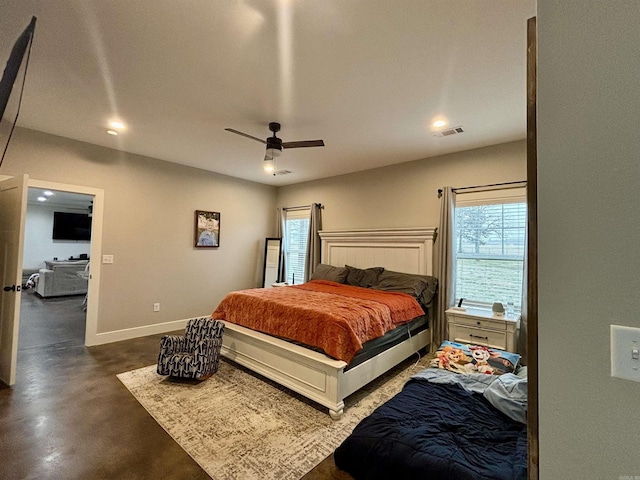 bedroom with ceiling fan, finished concrete flooring, visible vents, and baseboards