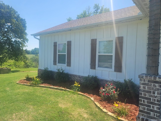 view of property exterior with a lawn, board and batten siding, and a shingled roof