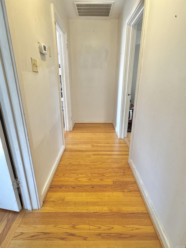 corridor featuring light wood-type flooring, visible vents, and baseboards