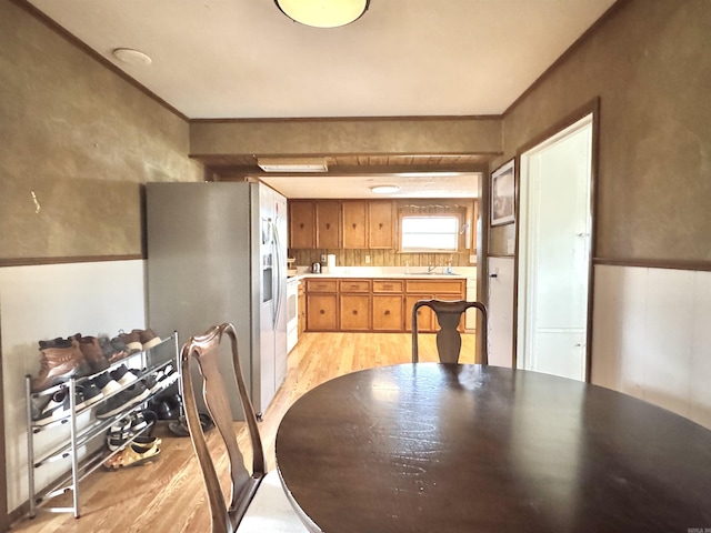 kitchen featuring brown cabinets, light wood-style flooring, ornamental molding, stainless steel refrigerator with ice dispenser, and light countertops