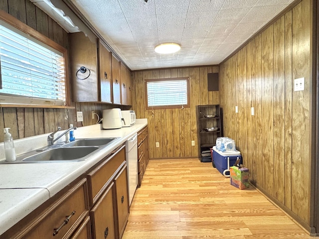 kitchen featuring white appliances, a sink, light countertops, light wood-style floors, and brown cabinets