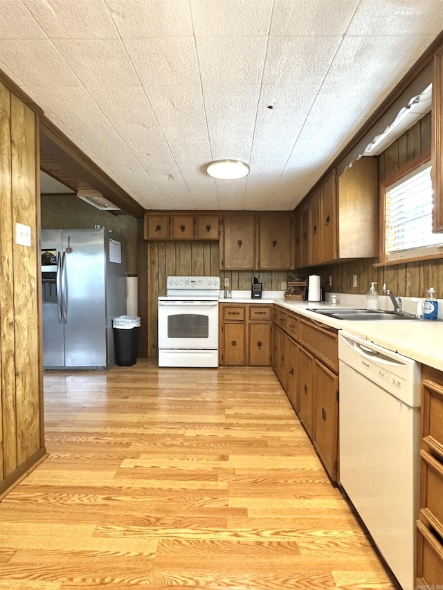 kitchen with white appliances, light countertops, light wood-type flooring, and a sink