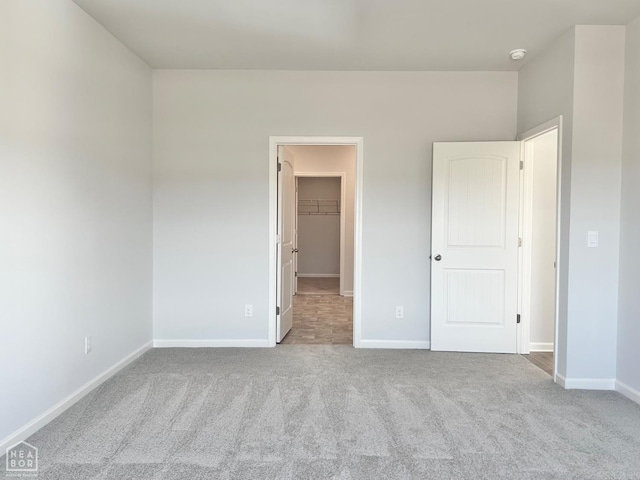 unfurnished bedroom featuring baseboards, carpet, and a spacious closet