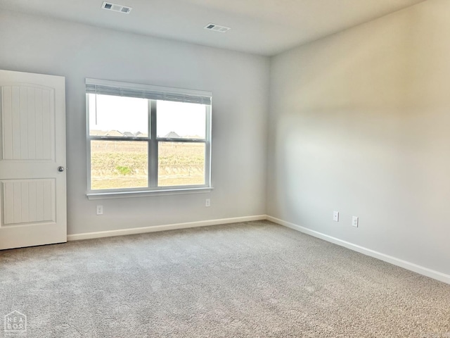 carpeted spare room featuring visible vents and baseboards