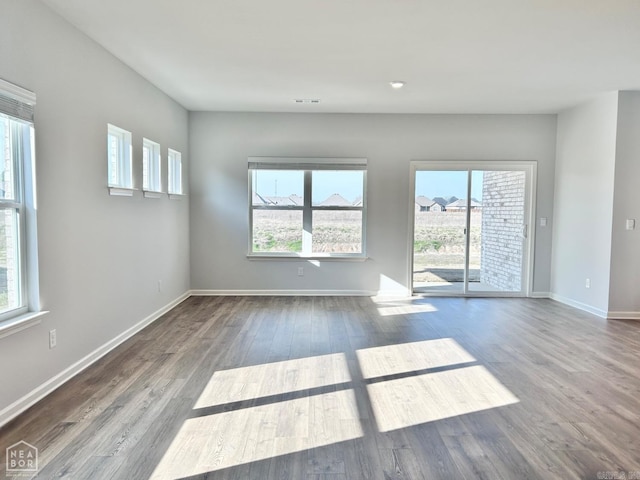 spare room with a healthy amount of sunlight, baseboards, and wood finished floors