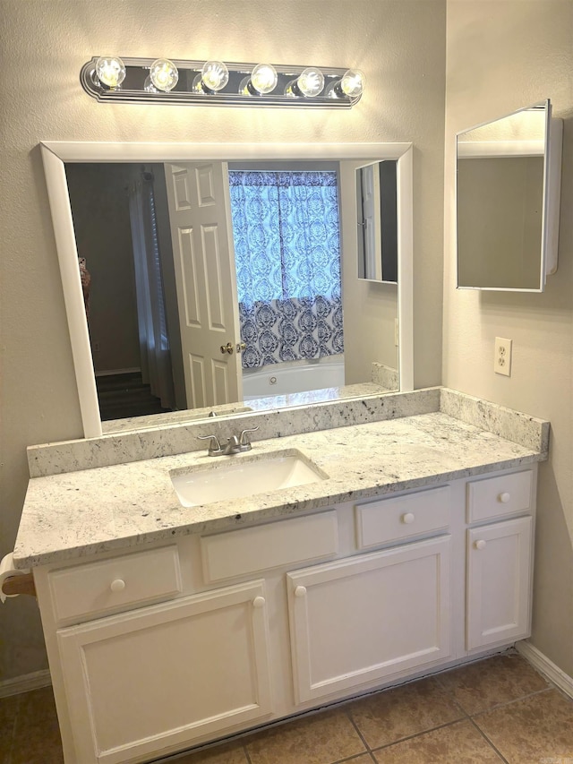 full bath with tile patterned floors, baseboards, a bathing tub, and vanity