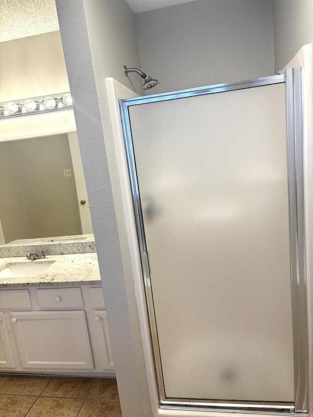 full bath featuring tile patterned floors, a stall shower, and vanity