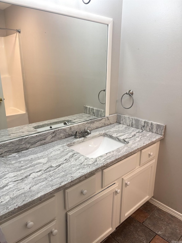 full bathroom with vanity, shower / bath combination, baseboards, and stone finish flooring