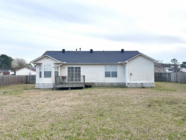 back of property featuring a yard, fence, and a shingled roof