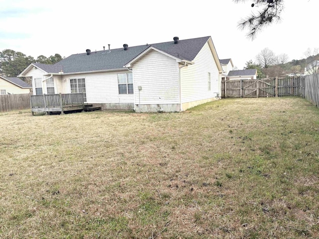 rear view of house featuring a lawn, a wooden deck, and a fenced backyard