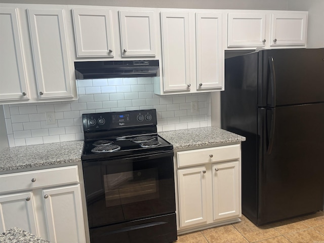 kitchen with under cabinet range hood, light stone countertops, backsplash, and black appliances