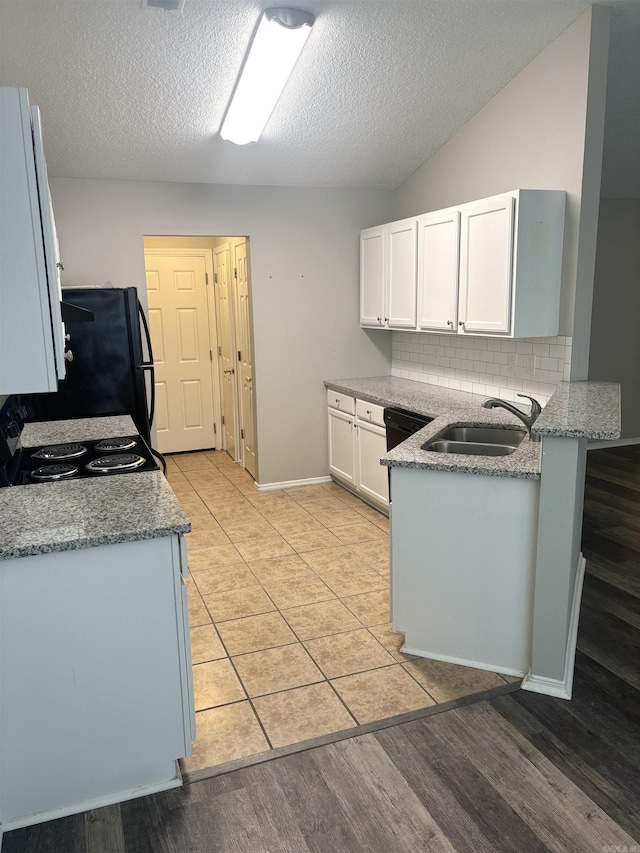 kitchen featuring light stone countertops, a peninsula, a sink, decorative backsplash, and white cabinets