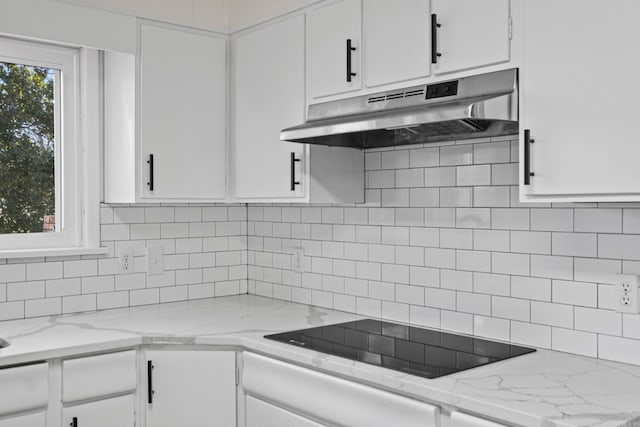 kitchen with light stone counters, decorative backsplash, under cabinet range hood, white cabinetry, and black electric stovetop