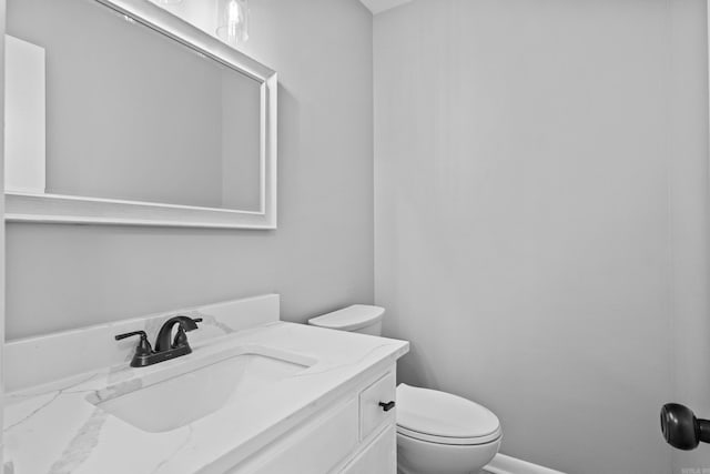 half bath featuring vanity, toilet, and baseboards