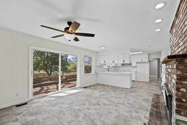 unfurnished living room with visible vents, a brick fireplace, baseboards, and a ceiling fan