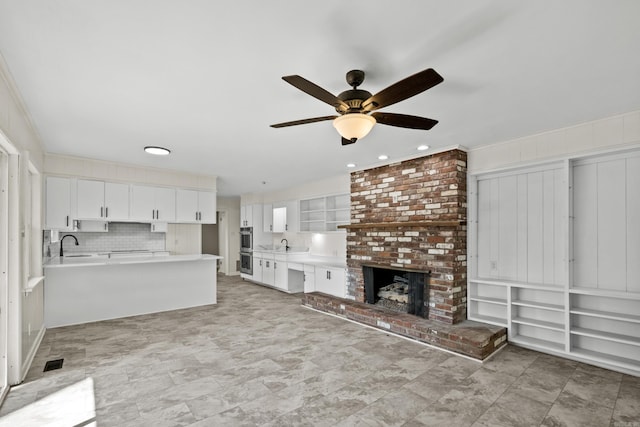 unfurnished living room featuring visible vents, a fireplace, ceiling fan, and a sink