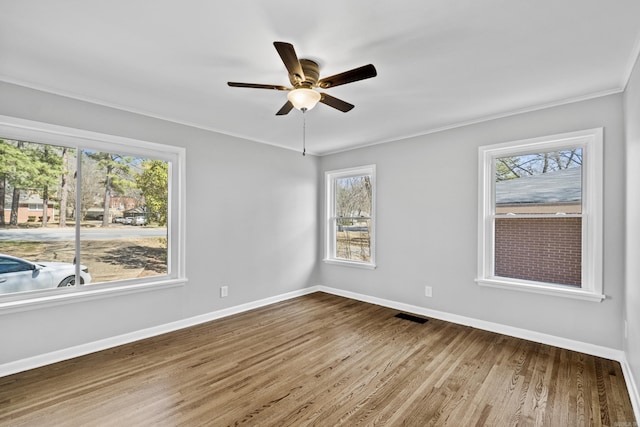 unfurnished room featuring wood finished floors, visible vents, baseboards, and ceiling fan