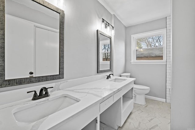 full bath featuring double vanity, toilet, baseboards, and a sink