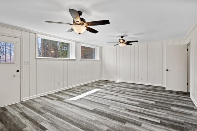 unfurnished living room featuring a wealth of natural light, baseboards, a ceiling fan, and wood finished floors