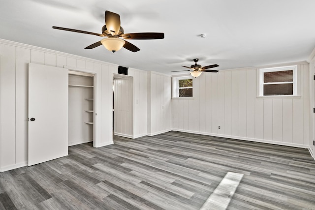 unfurnished bedroom with wood finished floors, baseboards, two closets, and ceiling fan