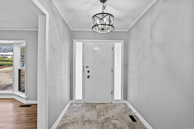 foyer with crown molding, a notable chandelier, visible vents, and baseboards