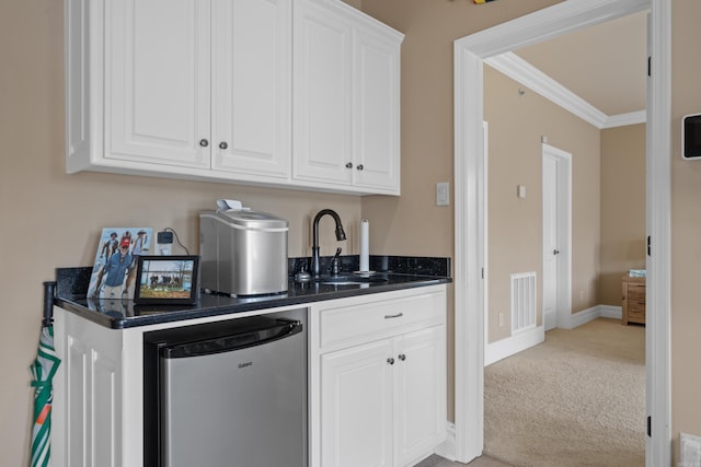 kitchen featuring dark countertops, visible vents, white cabinets, fridge, and light colored carpet